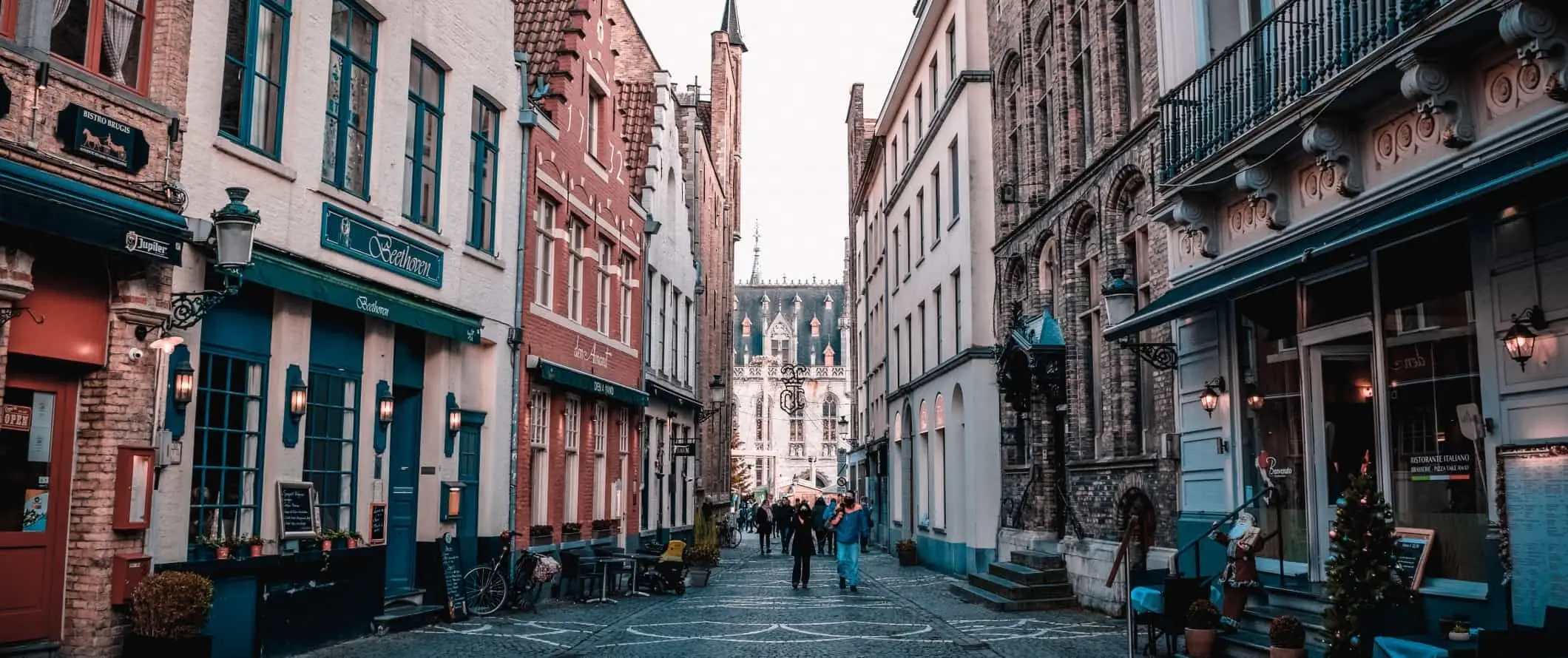 Menschen, die eine Fußgängerzone mit Kopfsteinpflaster im historischen Zentrum von Gent, Belgien, entlanggehen