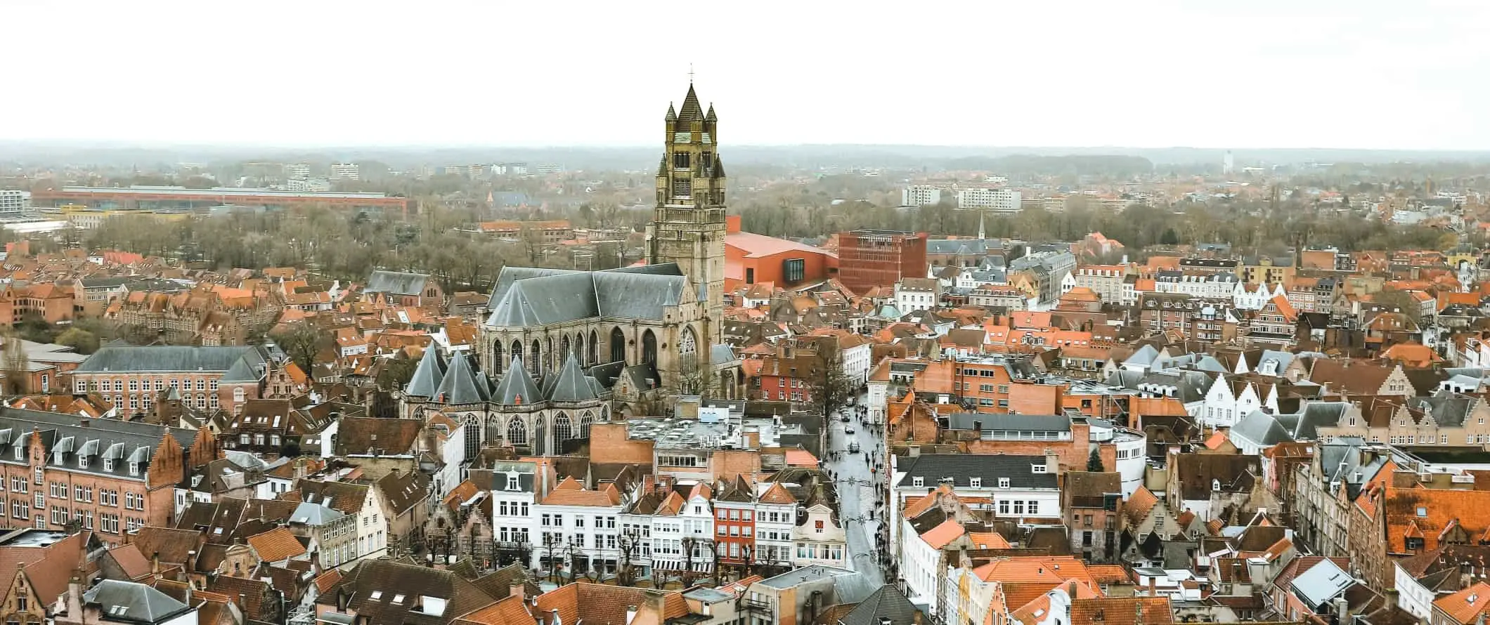 Vista panorâmica sobre os telhados vermelhos do centro histórico de Bruges, com uma grande catedral de pedra no centro, na Bélgica