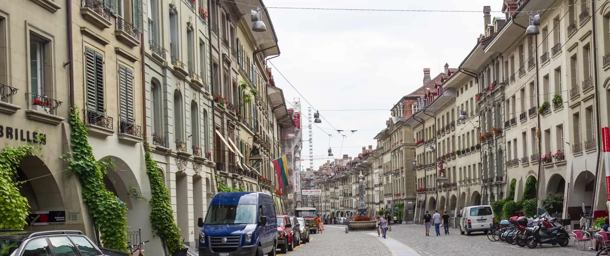 Žmonės, einantys akmenimis grįsta gatve istoriniame Berno centre, Šveicarijoje