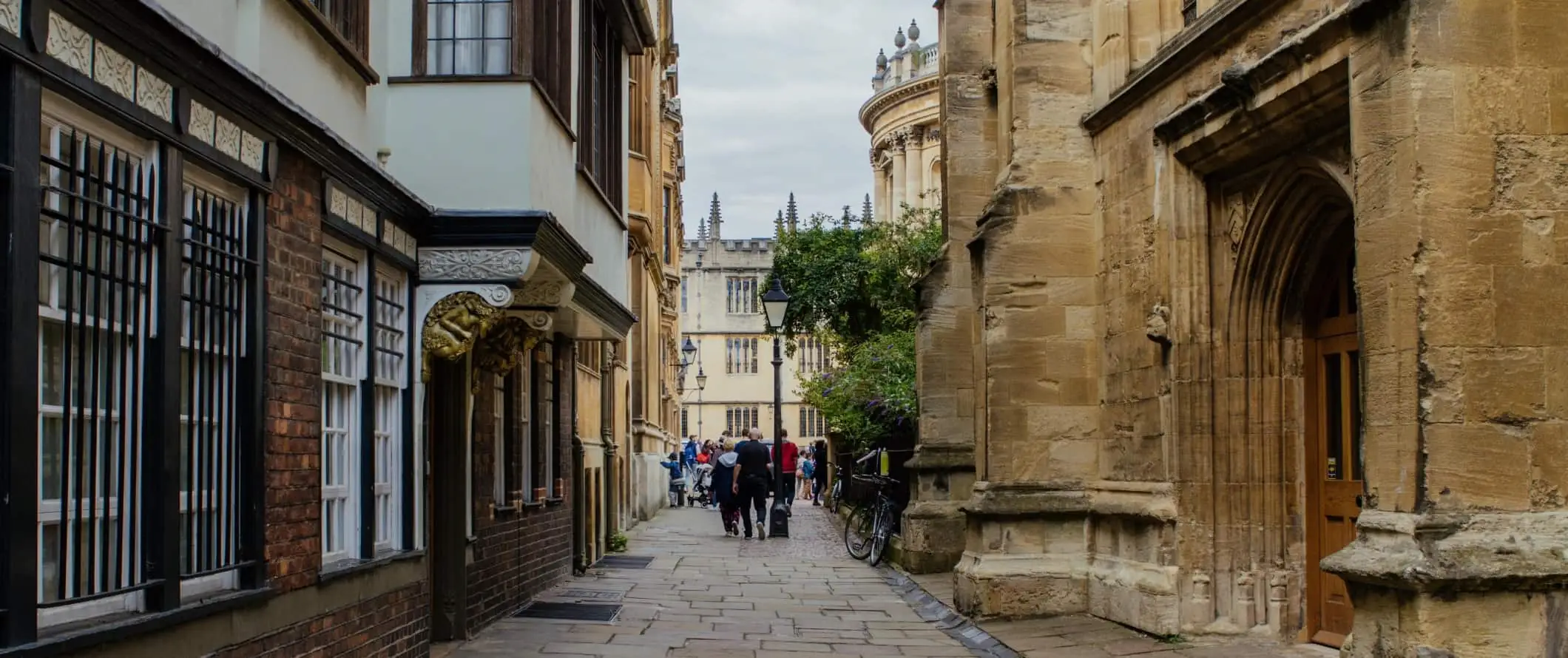 Gente caminando por una de las históricas callejuelas bordeadas de losas en la Universidad de Oxford, en la ciudad de Oxford, Inglaterra