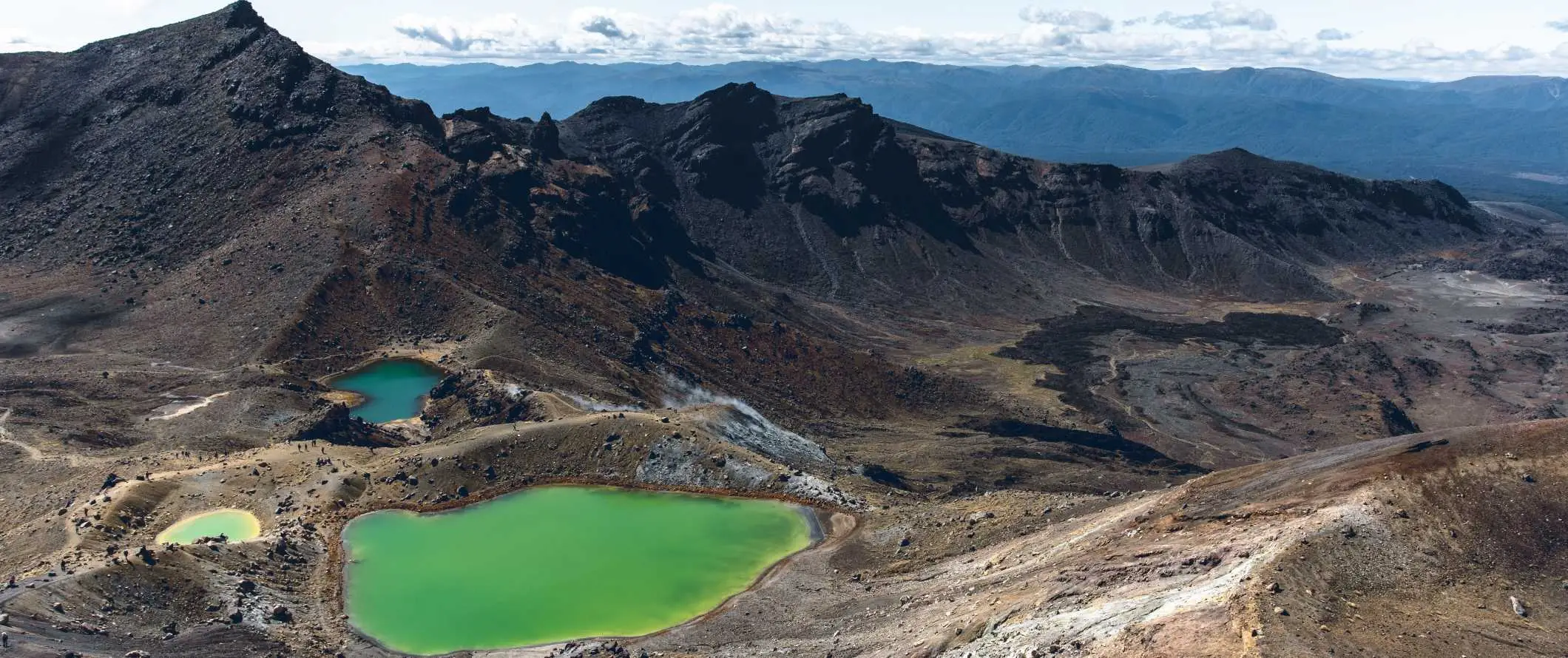 Dramatyczne krajobrazy wulkaniczne z jasnozielonymi jeziorami poniżej, przy Tongariro Alpine Crossing w pobliżu Taupo w Nowej Zelandii.