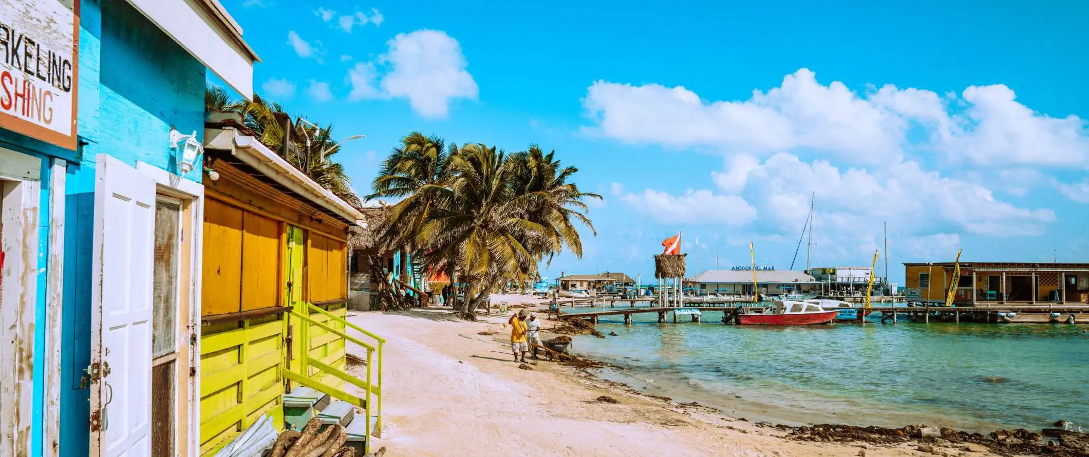 Bâtiments aux couleurs vives le long de la plage, bordés de palmiers tropicaux au Belize