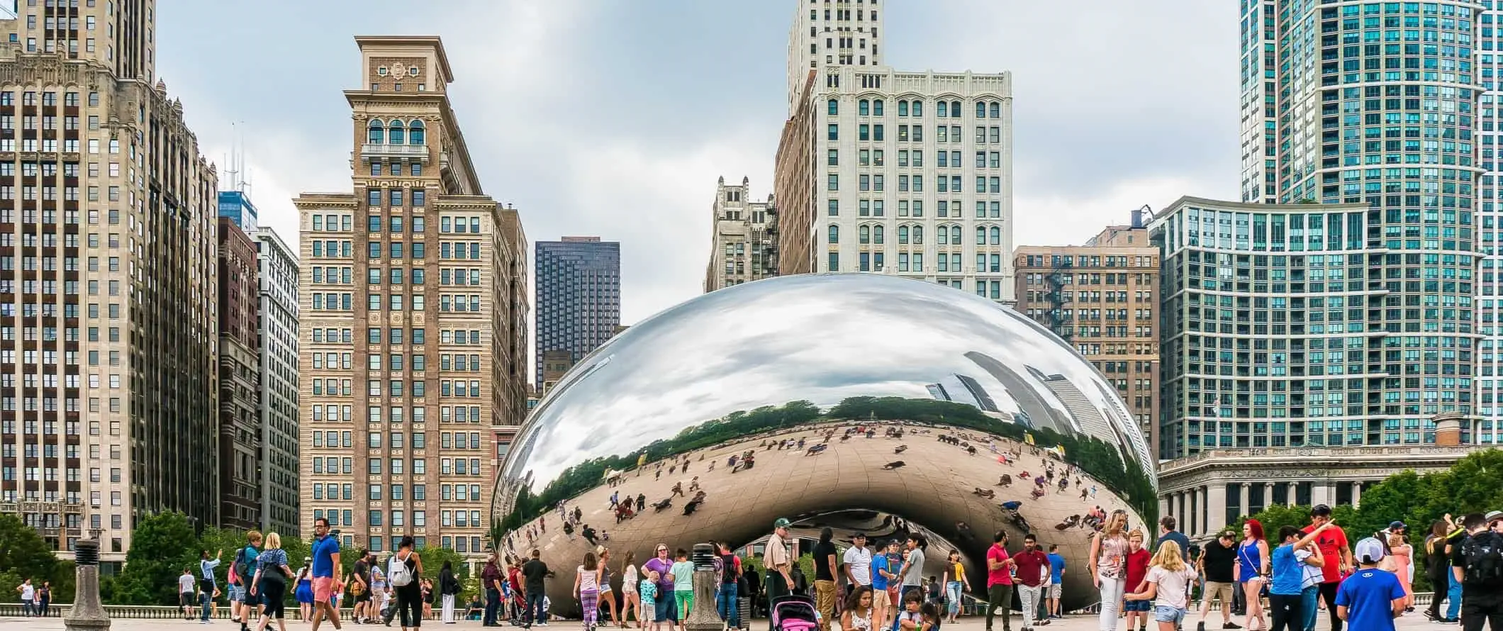 Ogromna, odblaskowa chromowana fasola z otaczającymi ją ludźmi i wysokimi budynkami za nią w Chicago, USA.