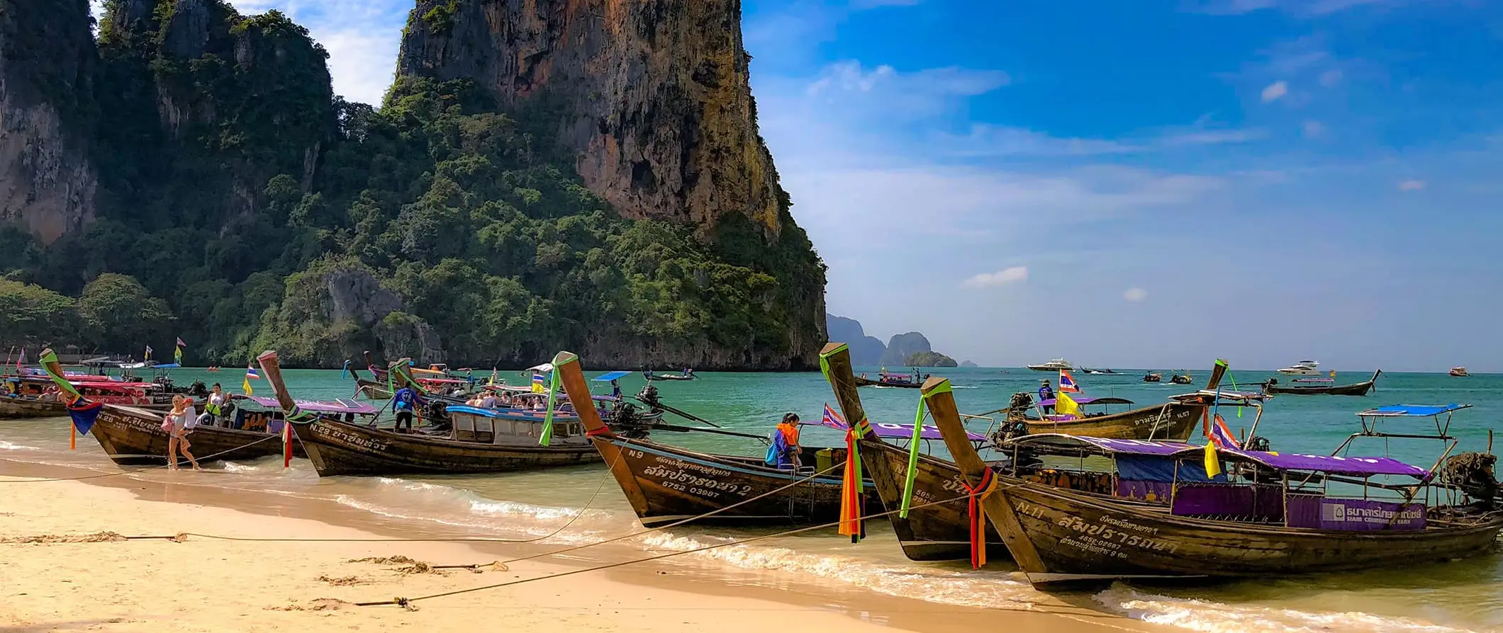 Een rij longtailboten geparkeerd op een prachtig strand in Thailand