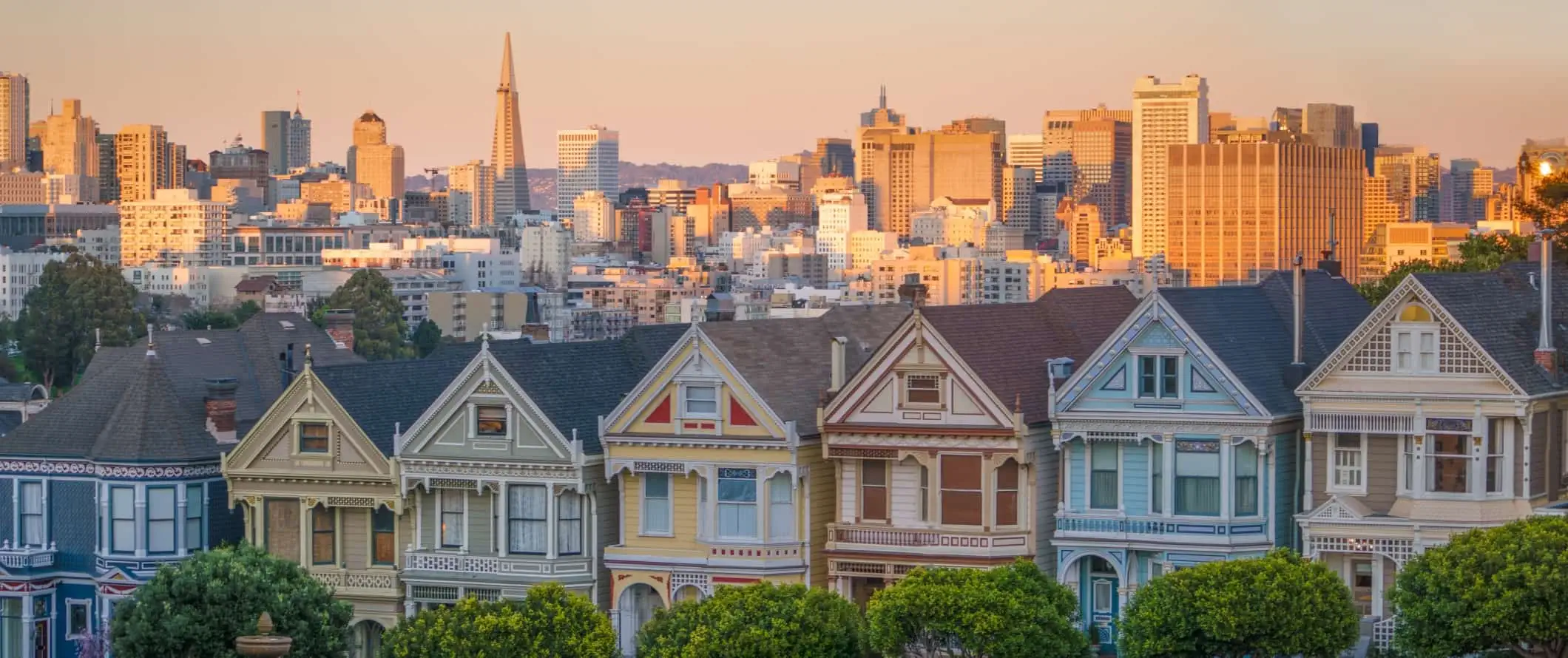 Skats uz gleznotajām dāmām, ikoniskām pasteļkrāsu Viktorijas laika mājām ar Sanfrancisko centra panorāmu fonā Sanfrancisko, Kalifornijā.