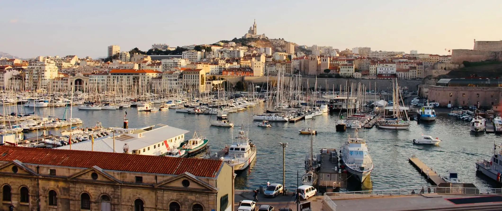 Pelabuhan lama yang dipenuhi dengan perahu layar, dengan bandar Marseille muncul di belakangnya di Perancis