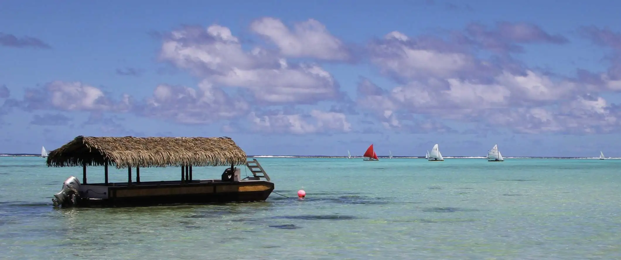 Bateau au toit de chaume garé dans les eaux claires des Îles Cook