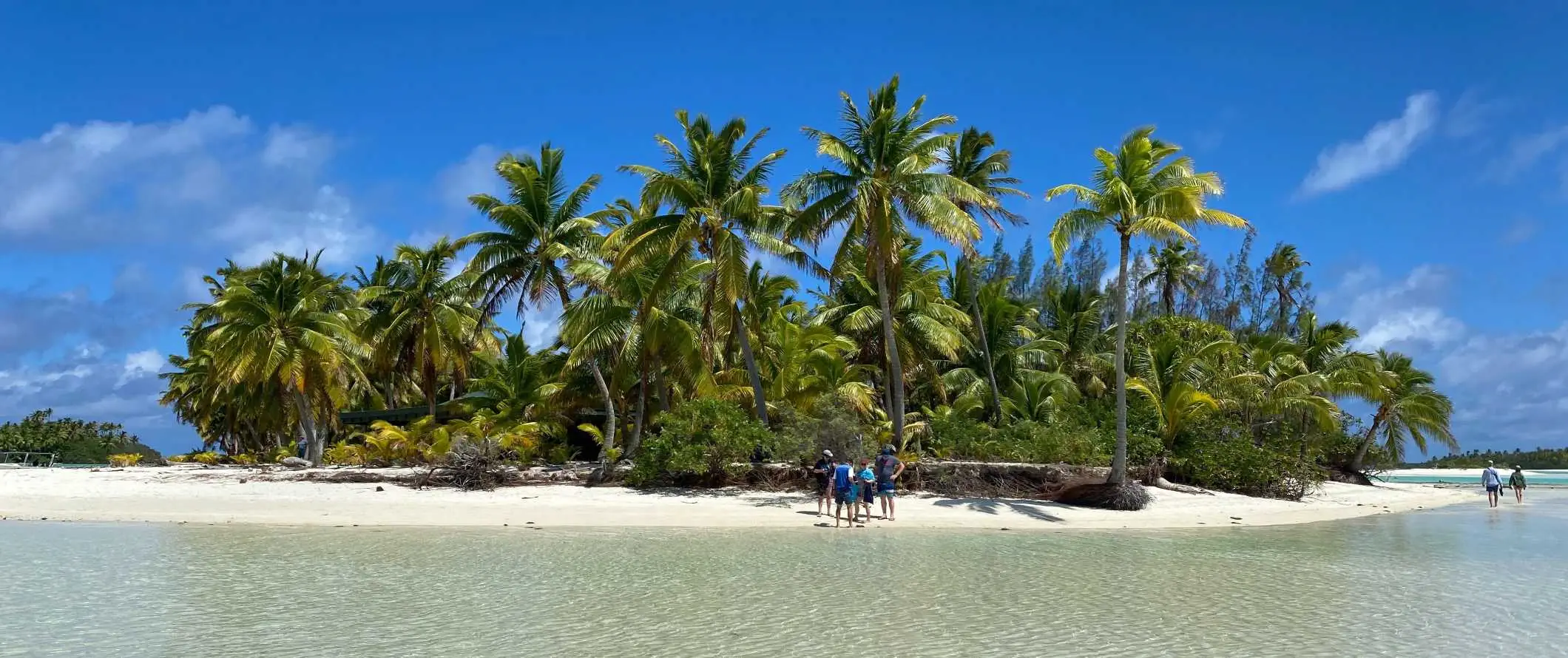 Gente de pie en una playa de arena blanca en la isla de Aitutaki en las Islas Cook