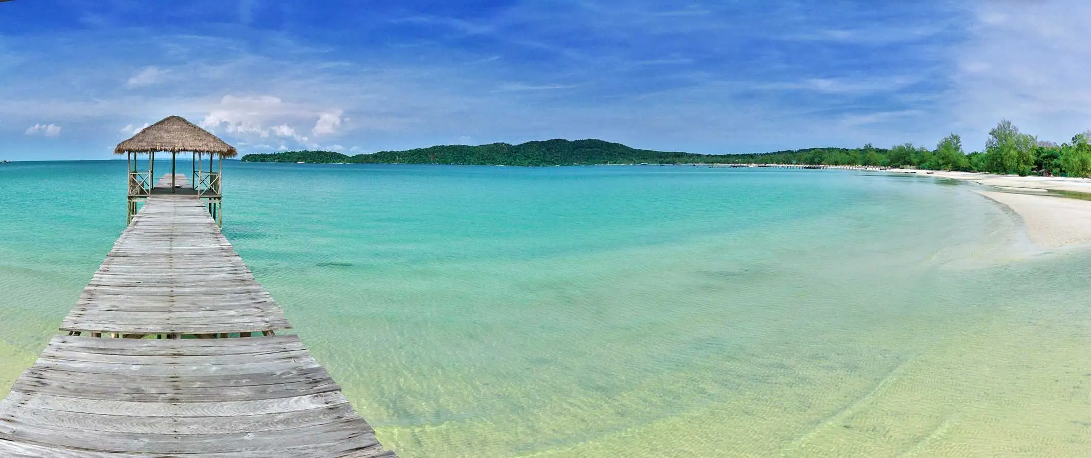 Chata kryta strzechą na końcu drewnianego doku wystającego w czystą turkusową wodę z białych piaszczystych plaż w Sihanoukville w Kambodży