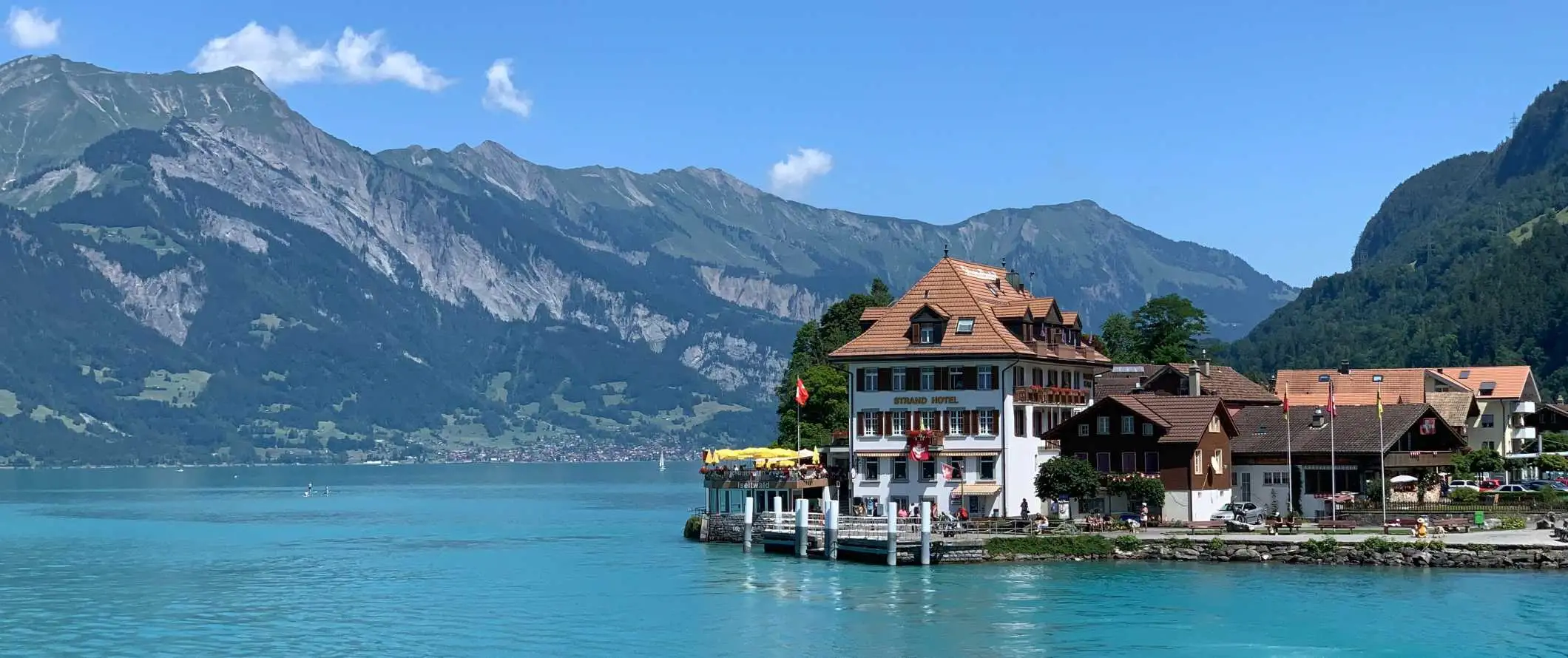 Hotel na skraju jasnoniebieskiego jeziora otoczonego górami w Interlaken w Szwajcarii