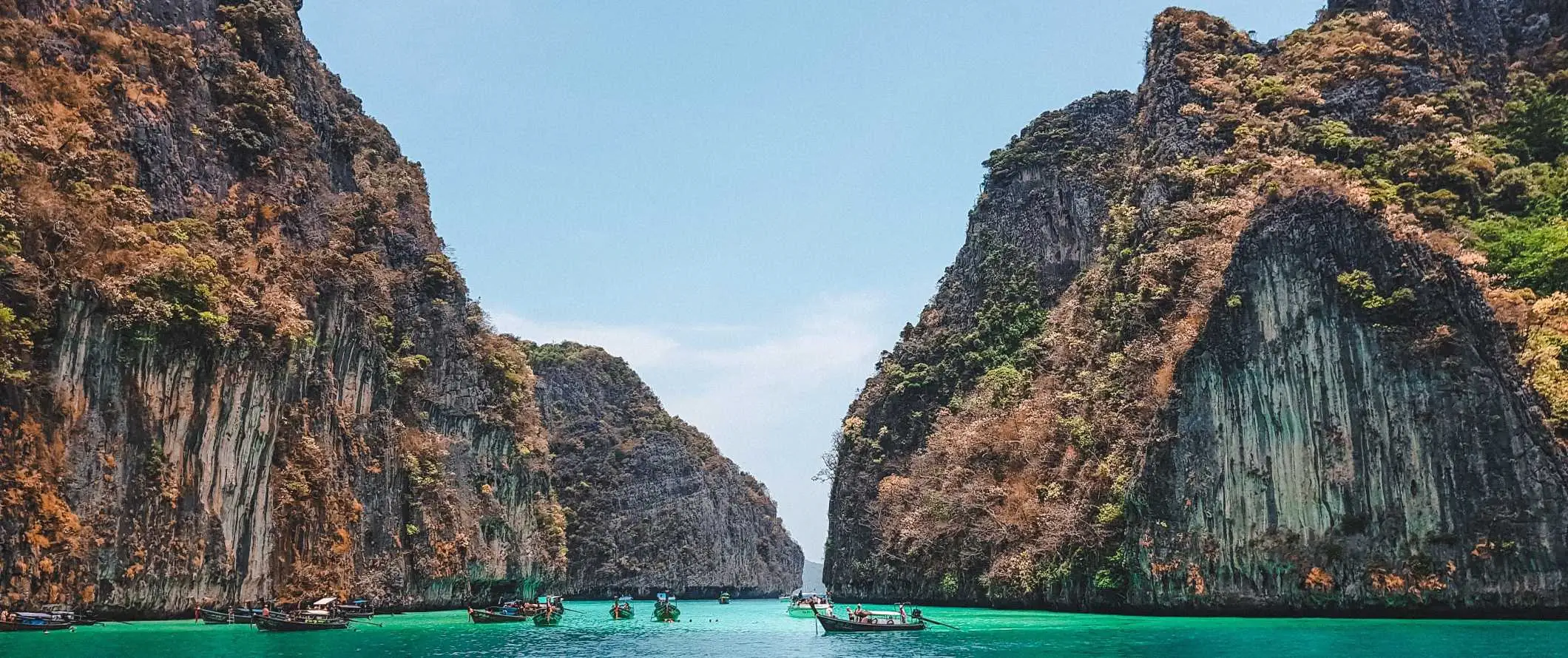 Båtar i vattnet framför enorma kalkstensformationer i Maya Bay på ön Ko Phi Phi, Thailand