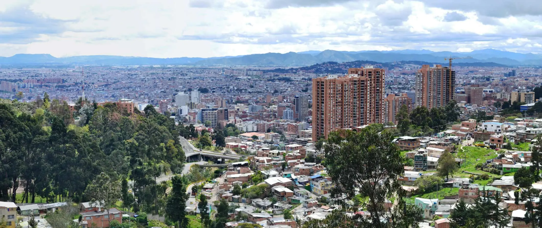 En byudsigt over Bogotá, Colombia med frodige grønne områder og bølgende bjerge i baggrunden