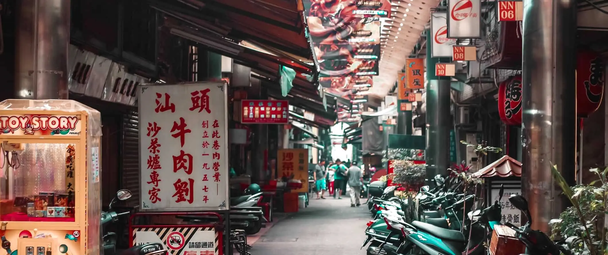 Une ruelle étroite bordée de scooters et de magasins dans un quartier animé de Taiwan