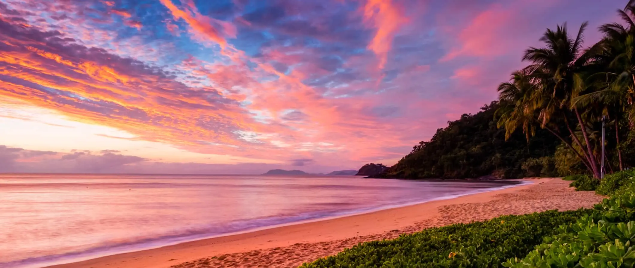 Un coucher de soleil rose vif au bord de l'eau à Cairns, en Australie