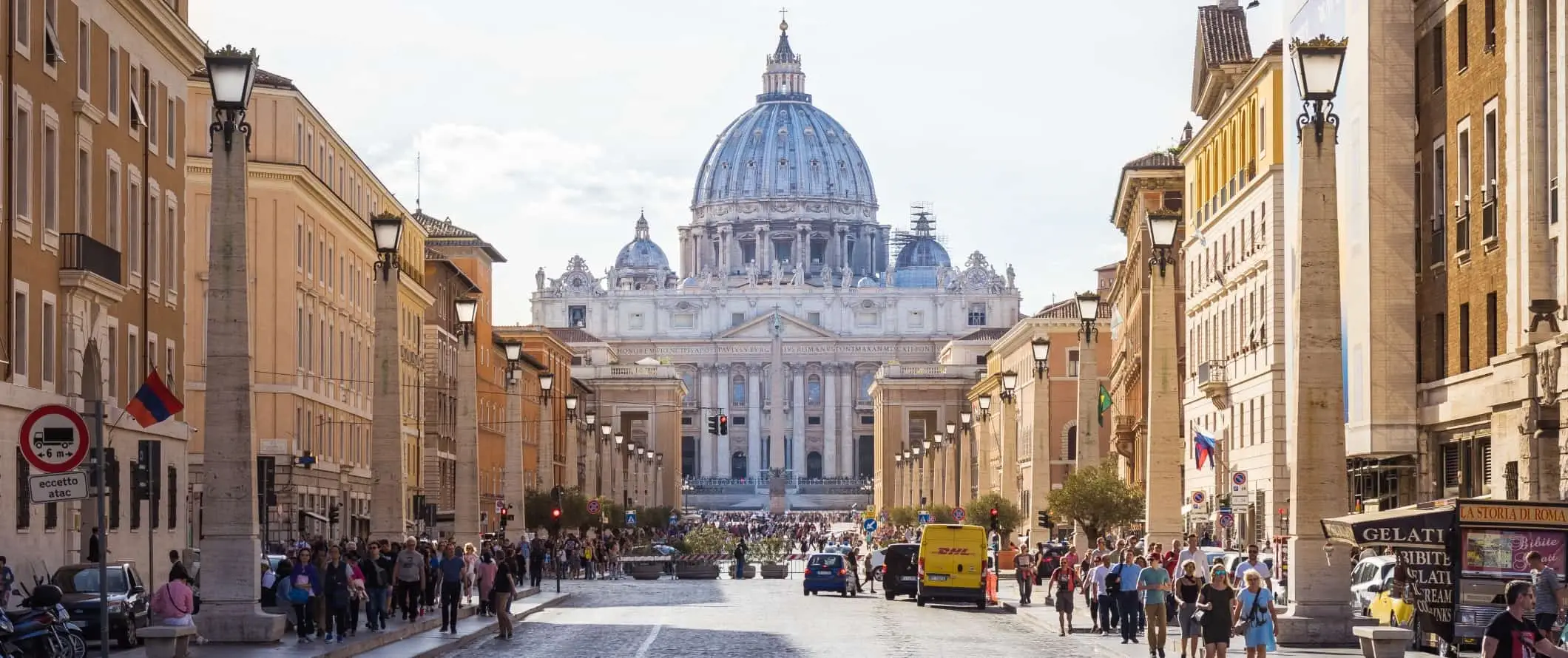 Ampia strada piena di gente e basilica alla fine a Roma, Italia