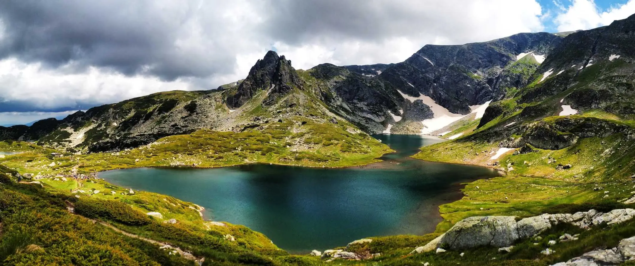 Smaragdo žalias ežeras su aštriomis dantytomis viršūnėmis fone Rilos kalnuose, Bulgarijoje