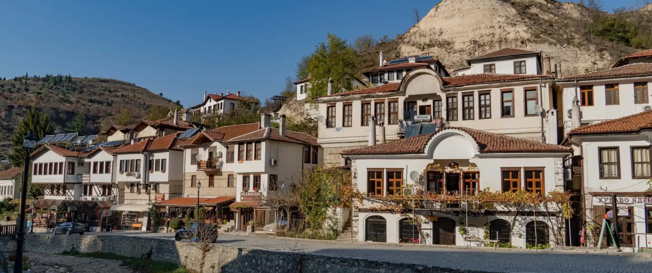 Traditionella bulgariska hus med terrakottatak längs en kullerstensgata i en liten by