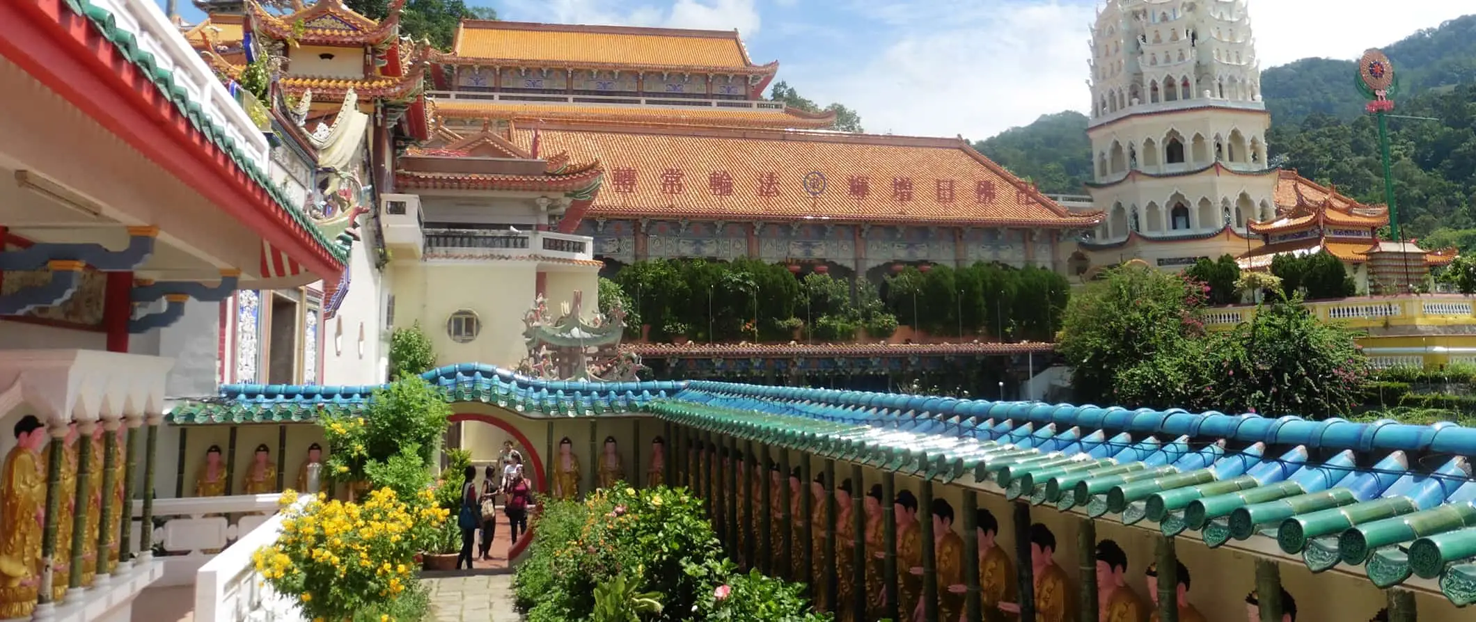 Färgglada historiska tempel i Malaysia en solig dag med böljande gröna kullar i bakgrunden