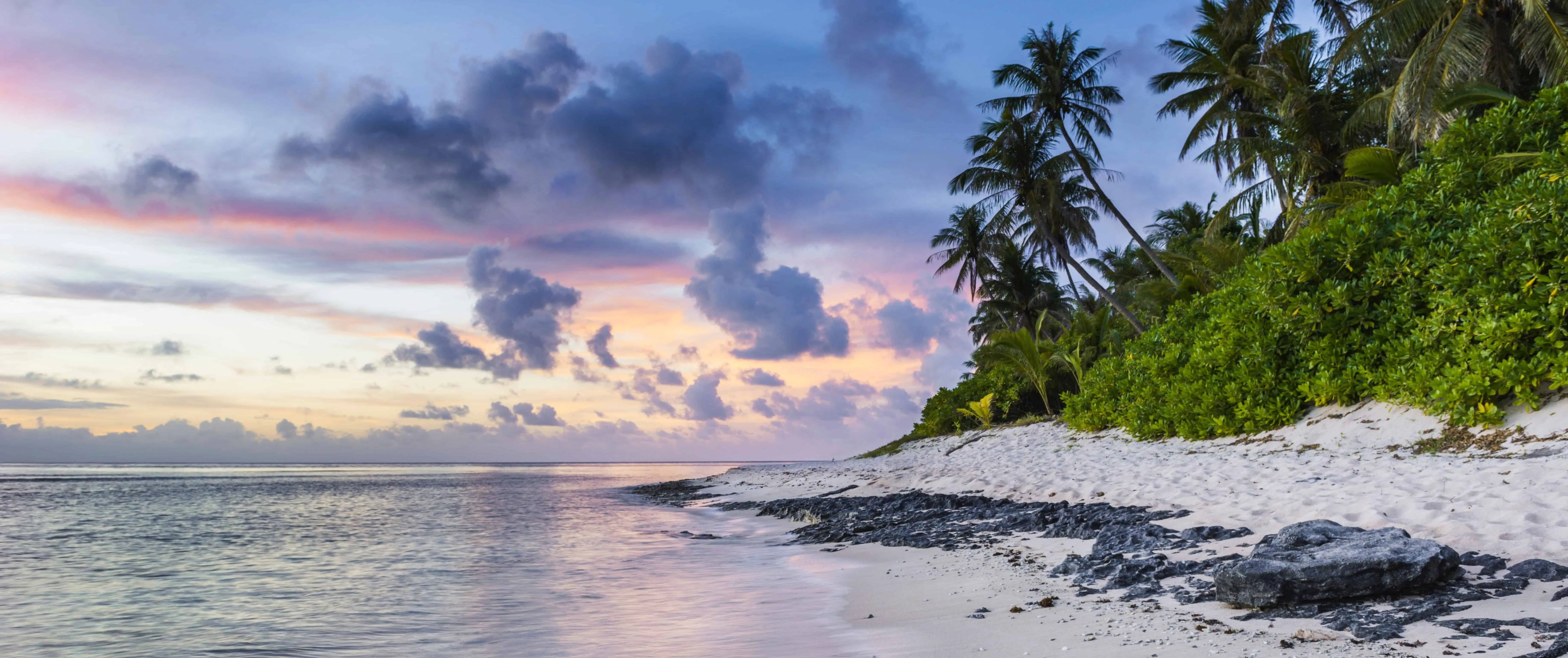 Een wit zandstrand met palmbomen bij zonsondergang in Jamaica