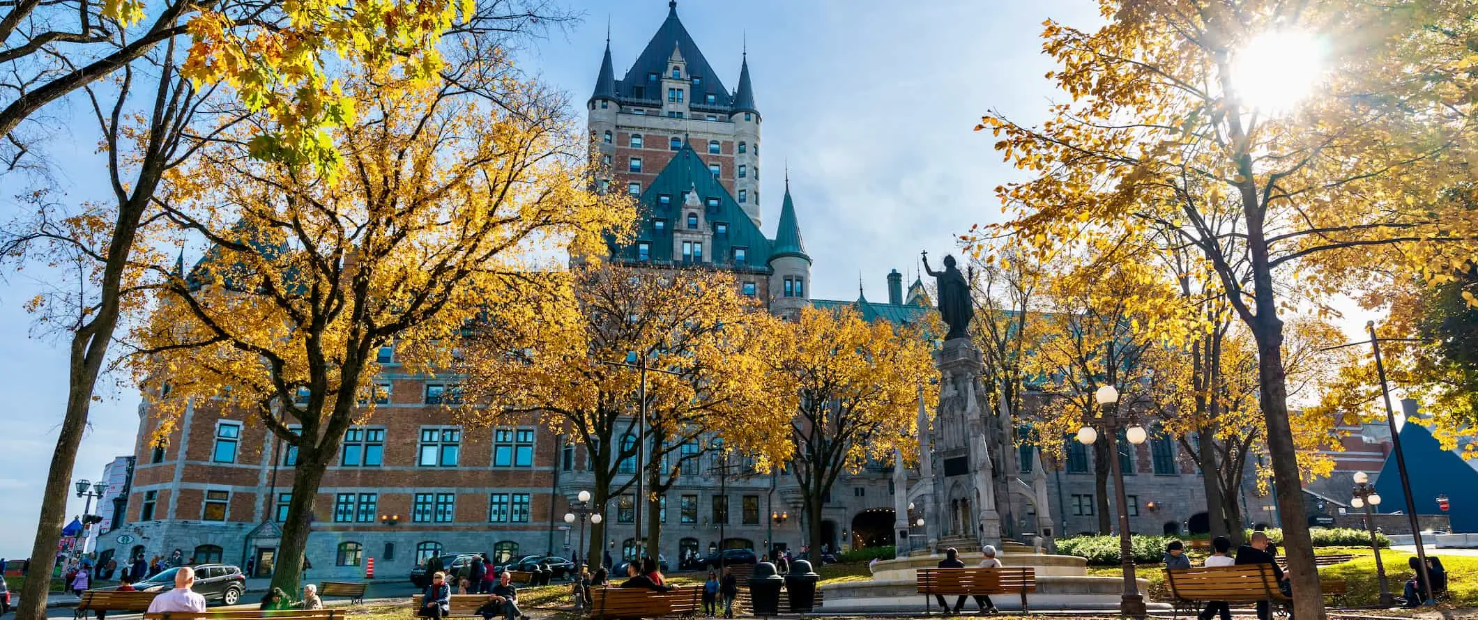 Mensen ontspannen in een zonnig park vlakbij een oud gebouw in Quebec City, Canada