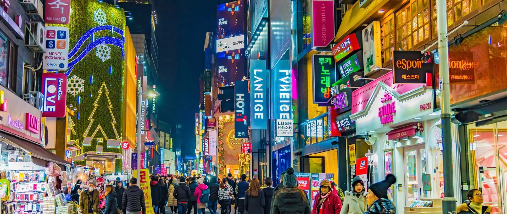 Locales y turistas en una concurrida calle de Seúl, Corea, por la noche, con muchos carteles luminosos