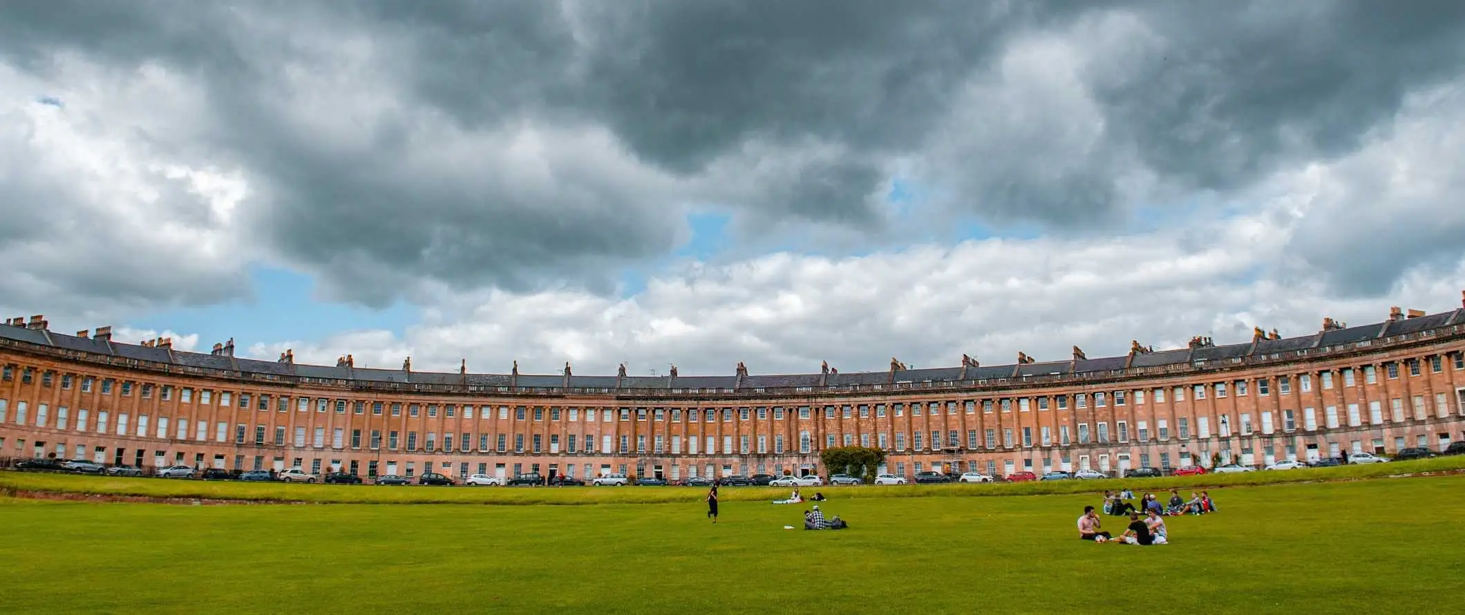 Bulan Sabit Diraja yang luas, deretan rumah bandar Georgia berbentuk bulan sabit dengan taman di hadapan di Bath, England