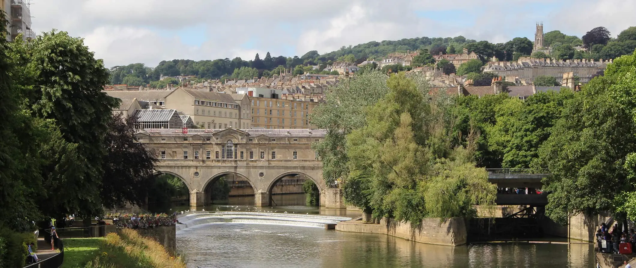 El puente histórico en Bath, Inglaterra, rodeado de árboles en un brillante día de verano.