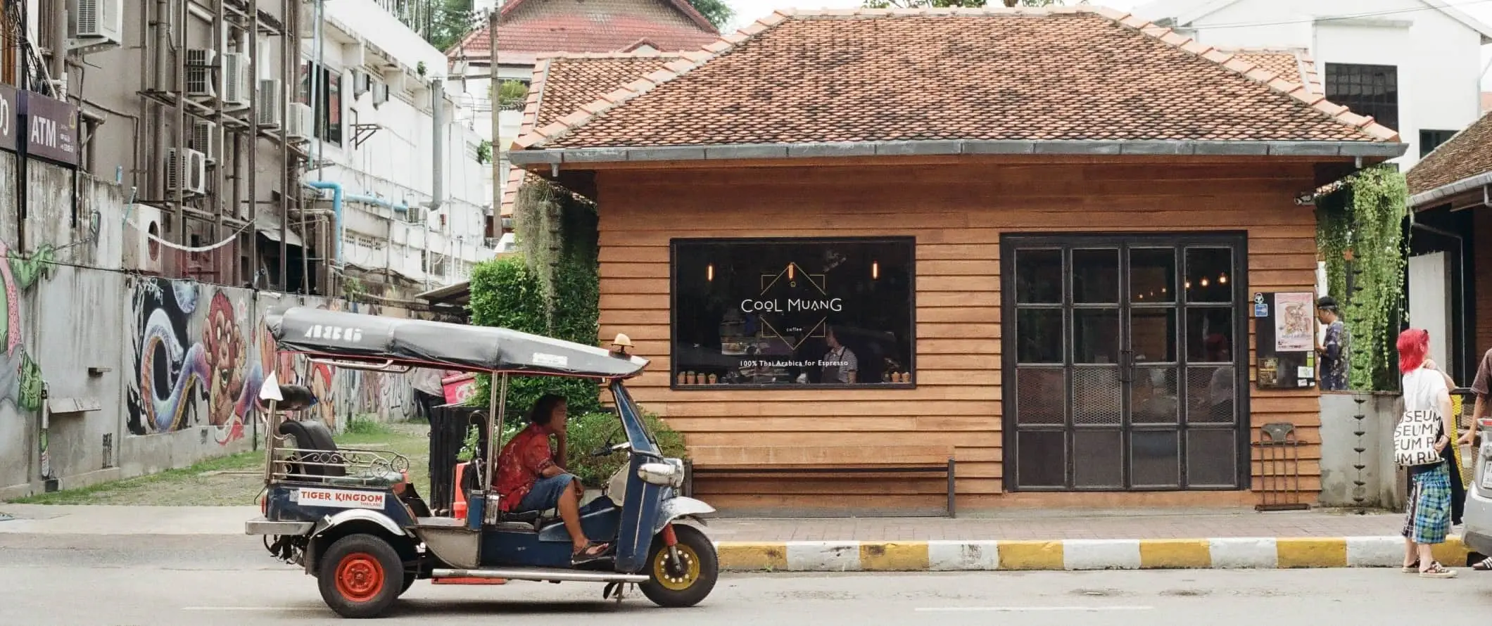 Person som kjører en rickshaw forbi en kaffebar mens folk går nedover gaten i Chiang Mai, Thailand