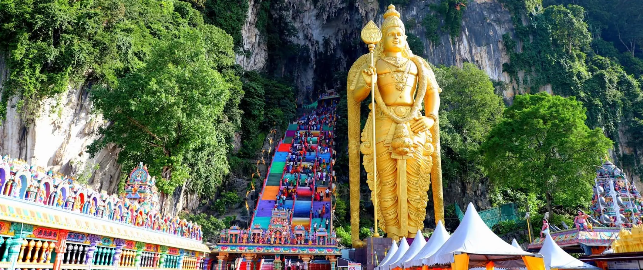 La entrada a las cuevas de Batu con escalones coloridos y una enorme estatua dorada de Arulmigu Murugan, una deidad hindú en Malasia