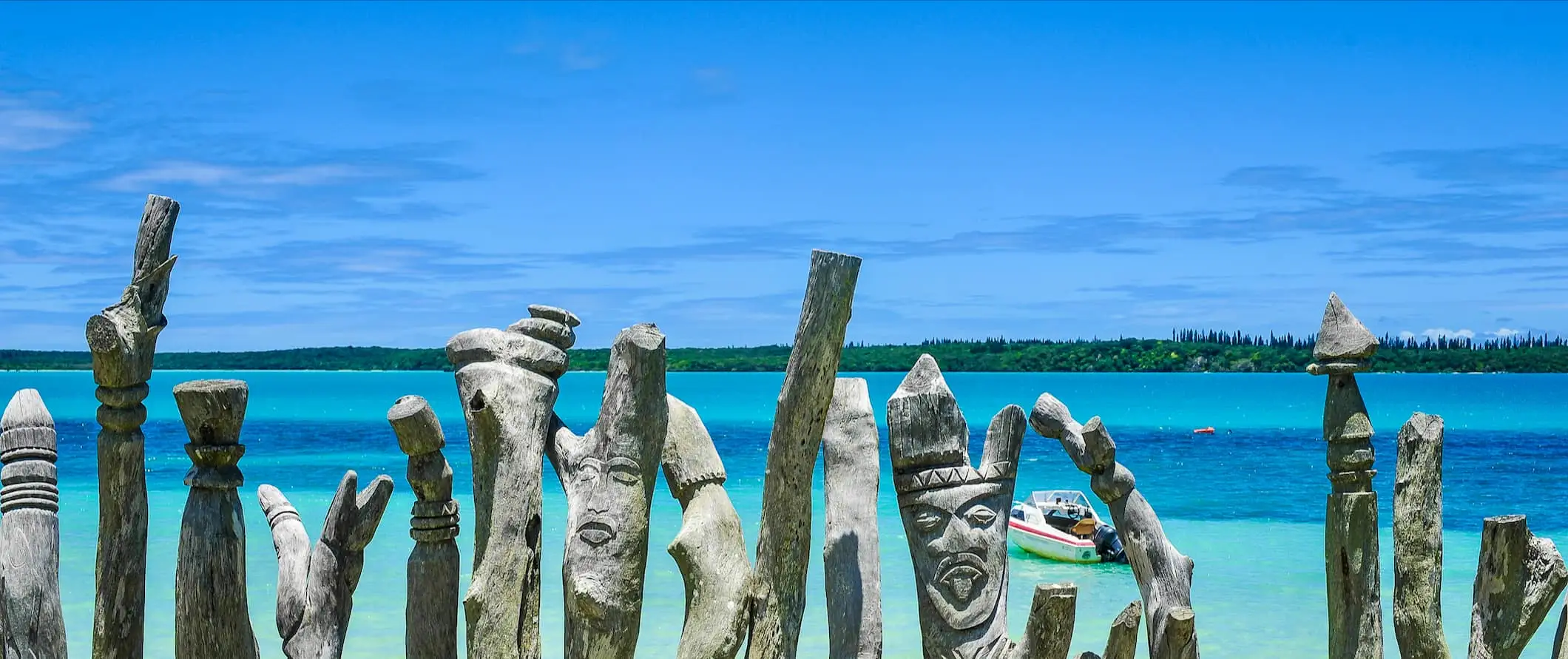 Udskårne træstolper nær stranden i solrige, lyse Vanuatu