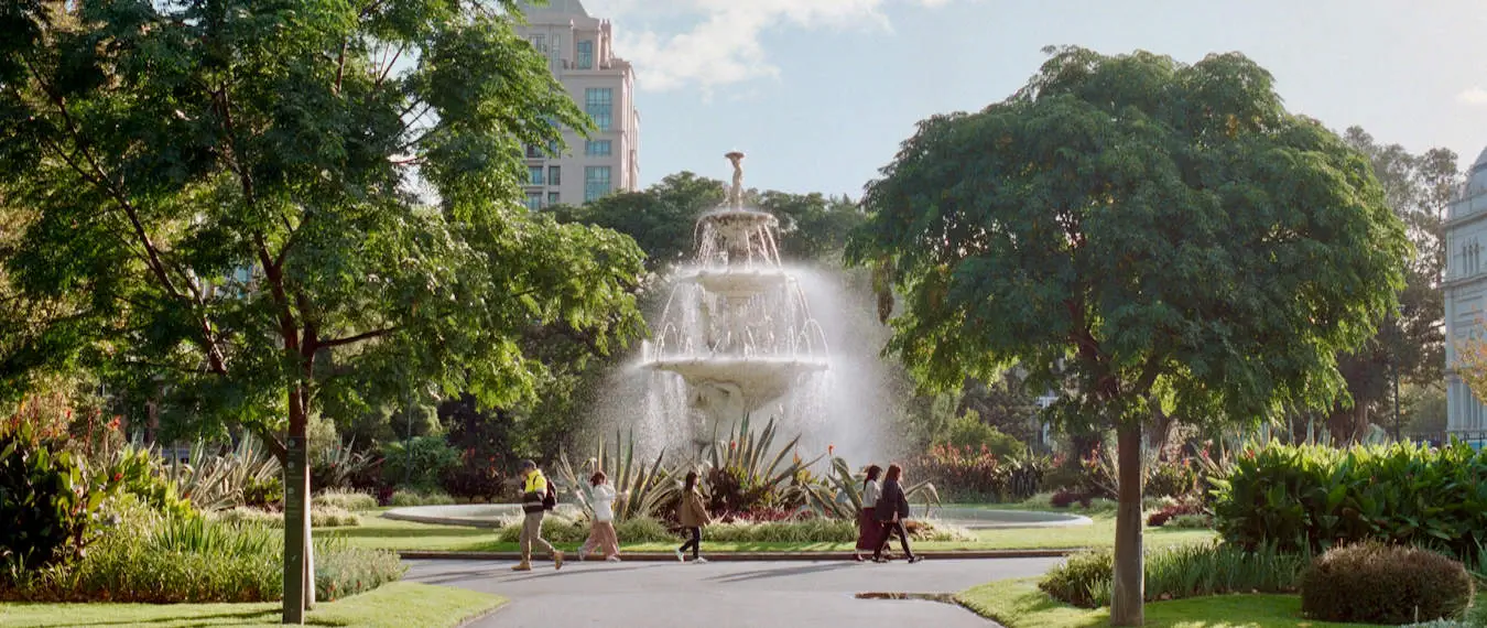 Isang fountain sa gitna ng isang berdeng parke sa maaraw na Melbourne, Australia