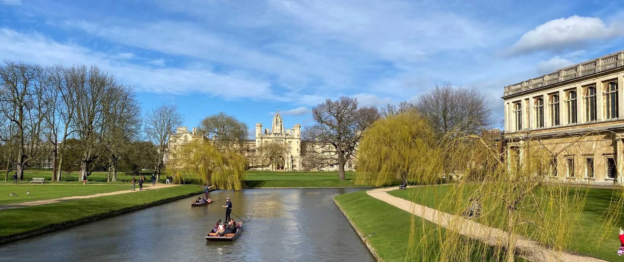 Ljudje se spuščajo po reki s stavbami univerze Cambridge v ozadju v Cambridgeu v Angliji