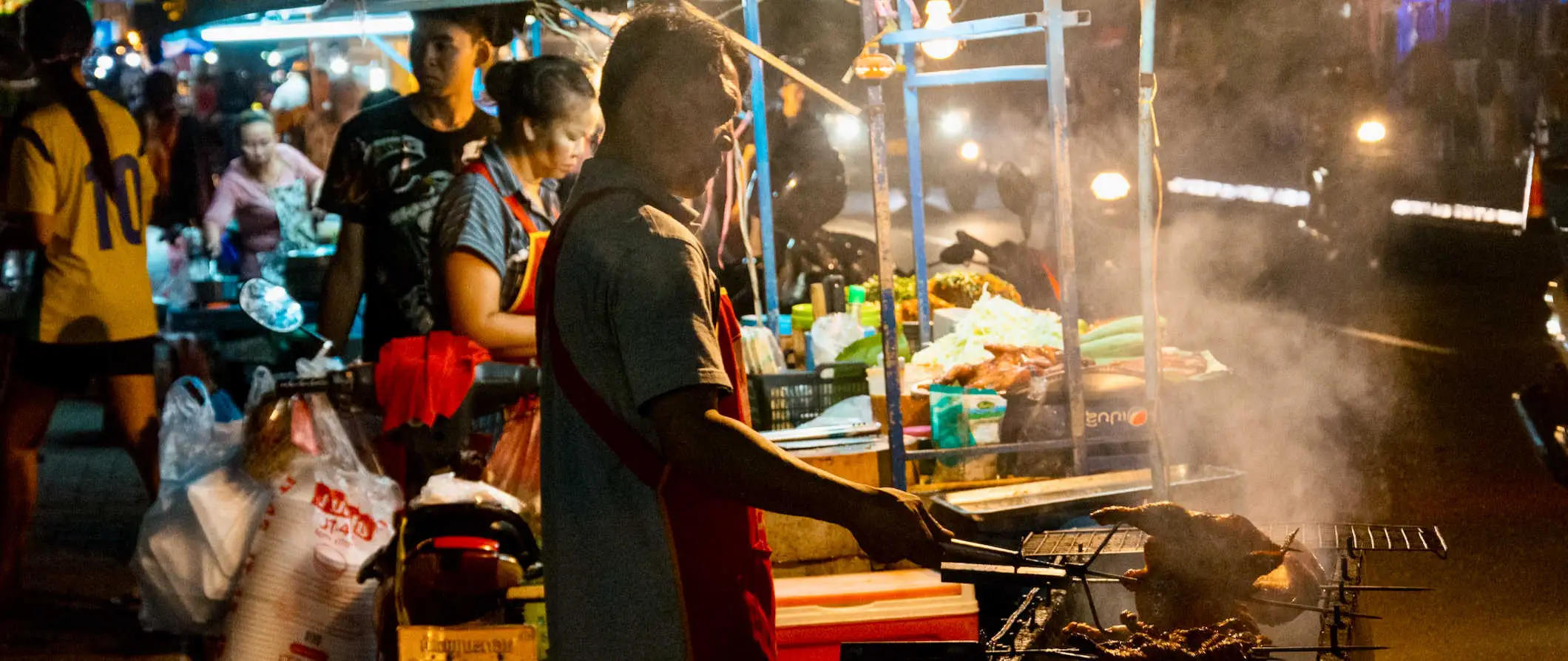 Vietinis Laoso gatvės maisto pardavėjas gamina maistą naktiniame turguje Vientiane, Laose