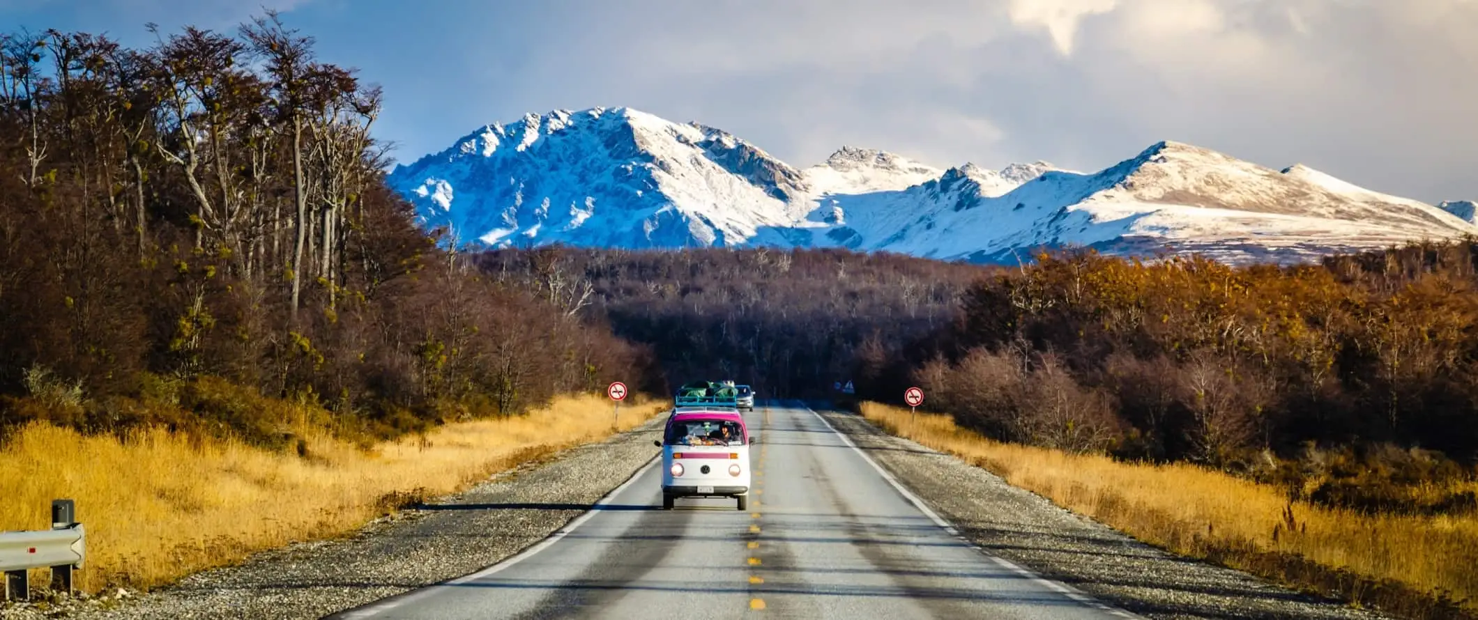 Un autobús d'època condueix per una carretera amb un espectacular teló de fons muntanyós a l'Argentina