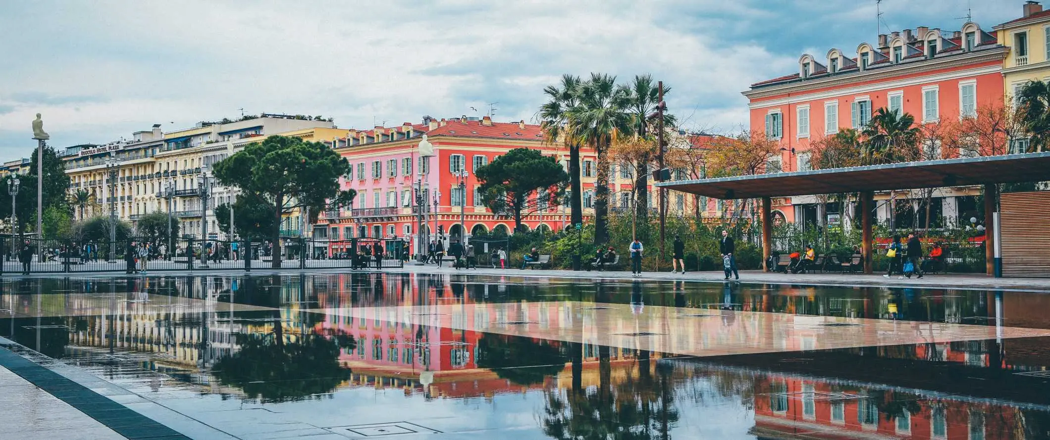 Una àmplia font i piscina reflectant amb els edificis de colors de Niça, França al fons en un dia trist