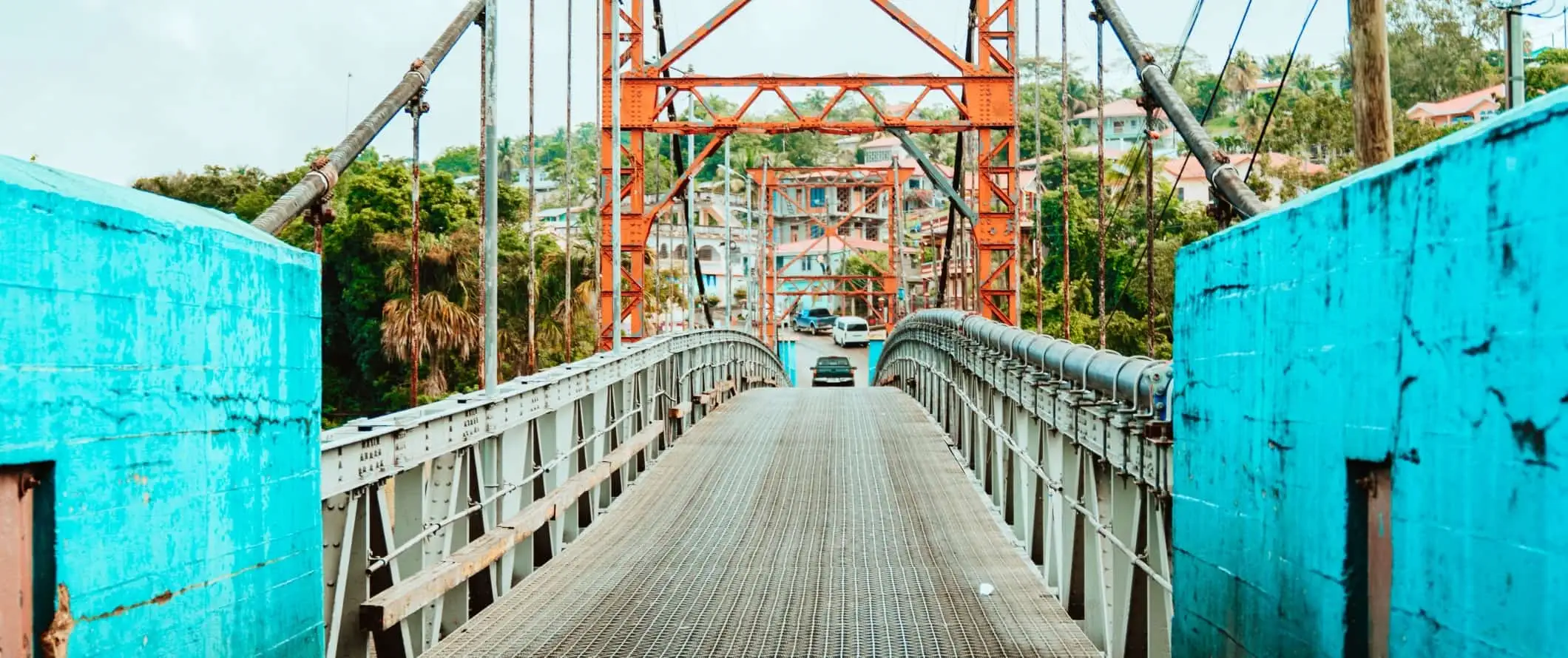 Jambatan logam dengan dinding biru terang dan sebuah kereta memandu di atasnya di San Ignacio, Belize