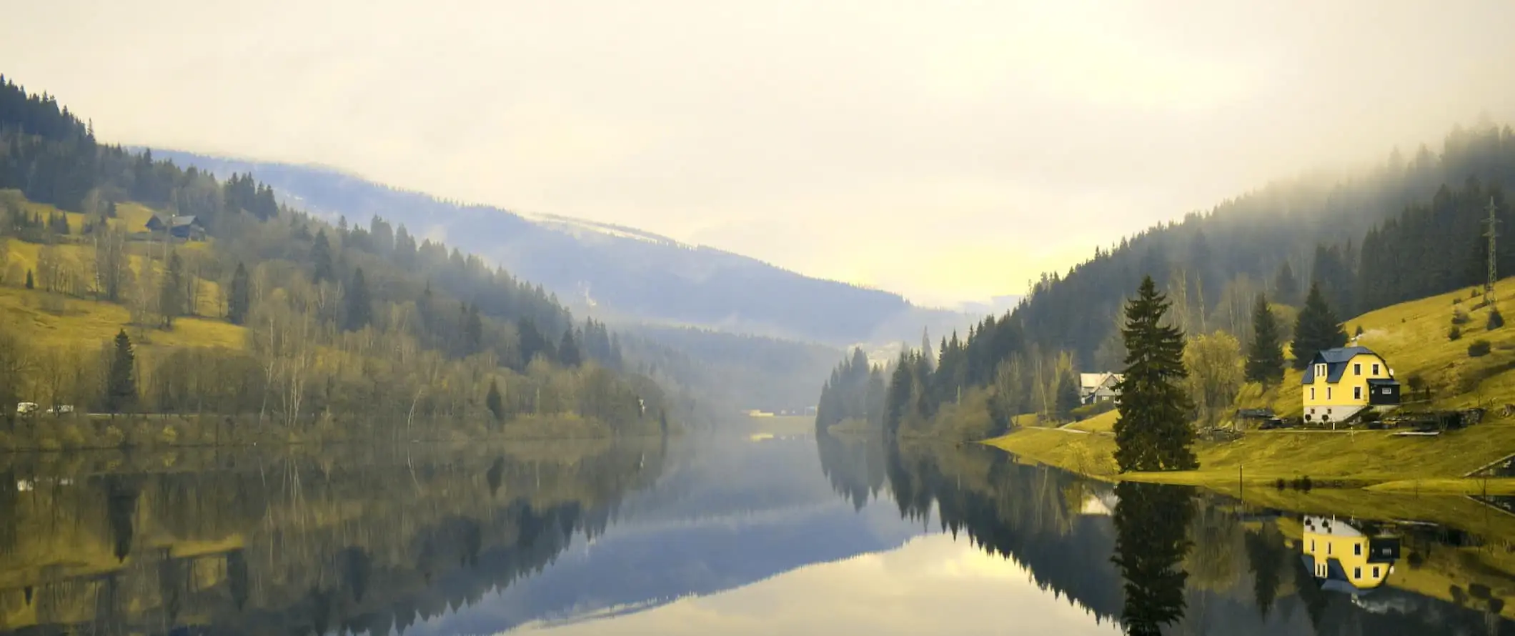 Sebuah danau tenang yang dikelilingi perbukitan di pedesaan Czechia