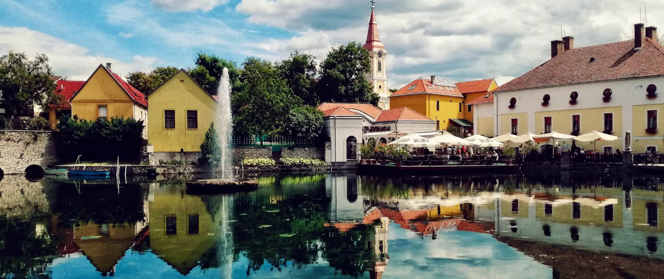 isang makulay at makasaysayang bayan sa Hungary, na may repleksyon sa kalmadong tubig