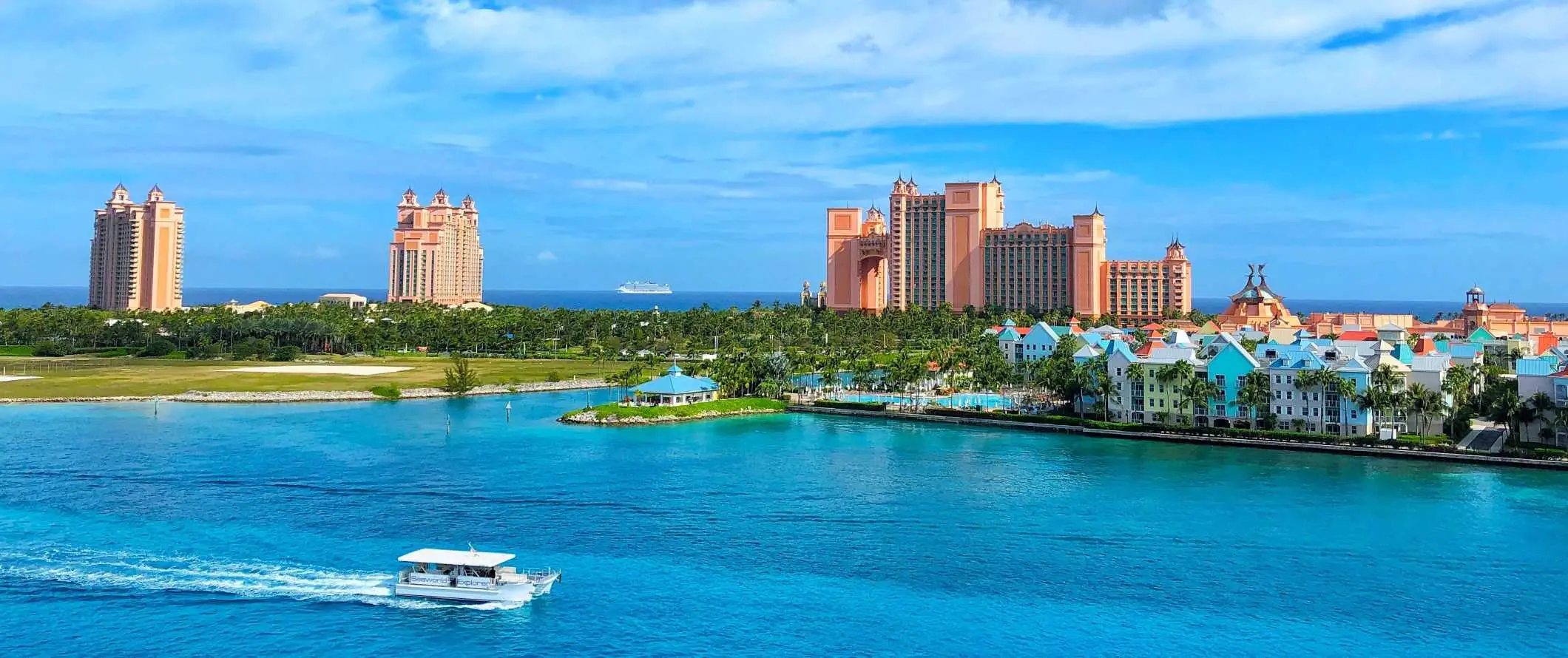 Atlantis hotellkomplex i bakgrunden med en båt som går förbi klarblått vatten i förgrunden, på Bahamas