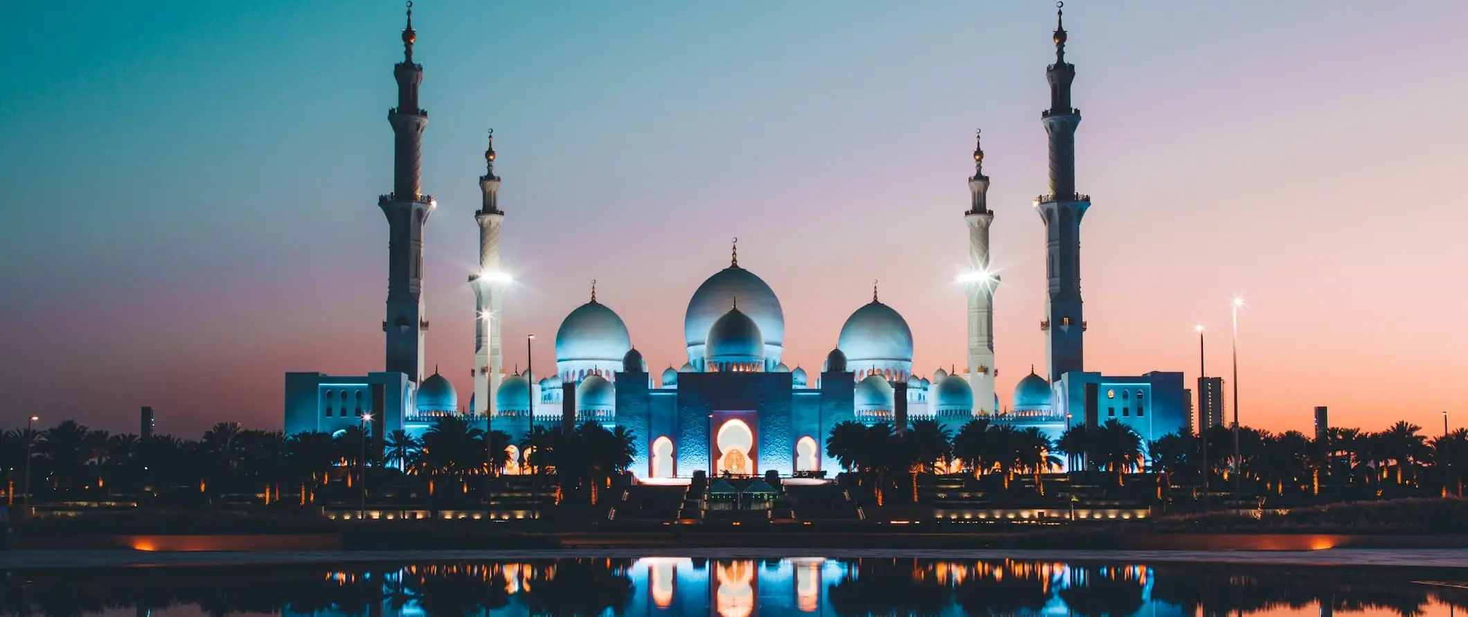 Una enorme mezquita iluminada por la noche cerca del agua de Dubai