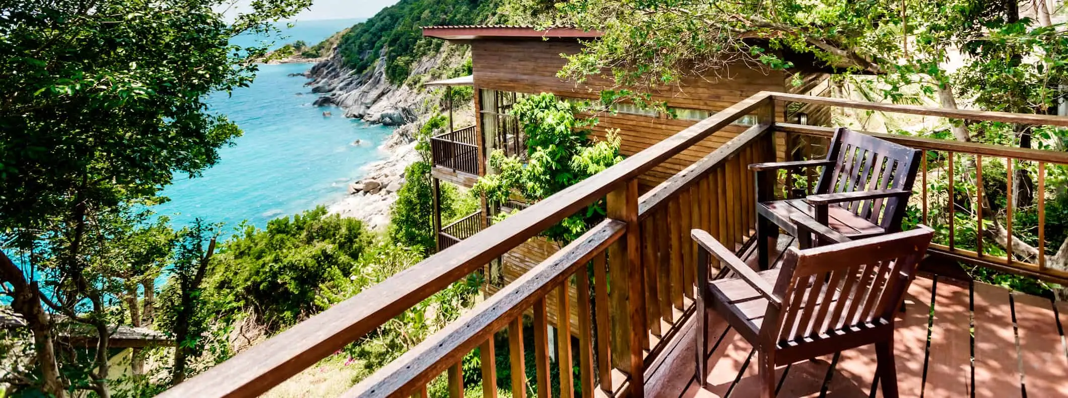 Zwei Holzstühle auf einer Veranda mit Blick auf eine wunderschöne, üppige Landschaft