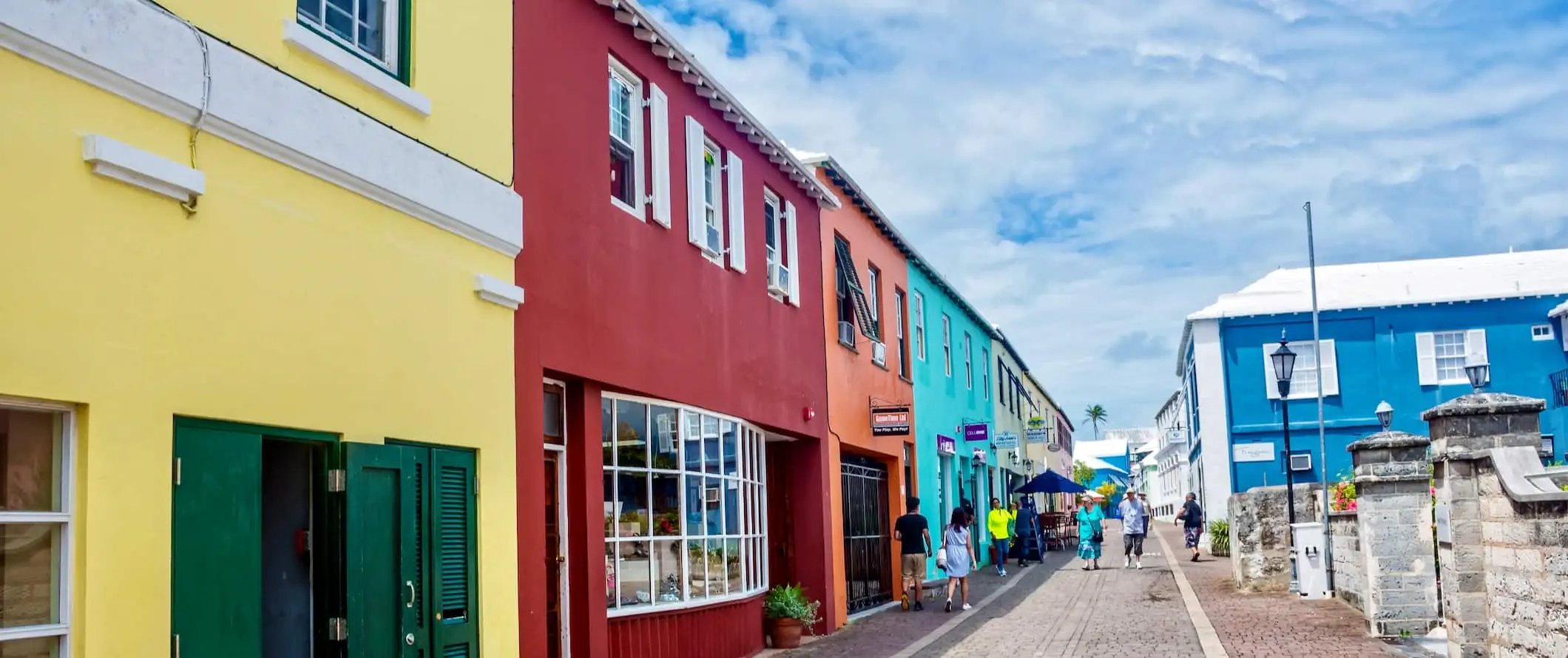 Folk som går nedover en gågate med fargerike hus på Bermuda