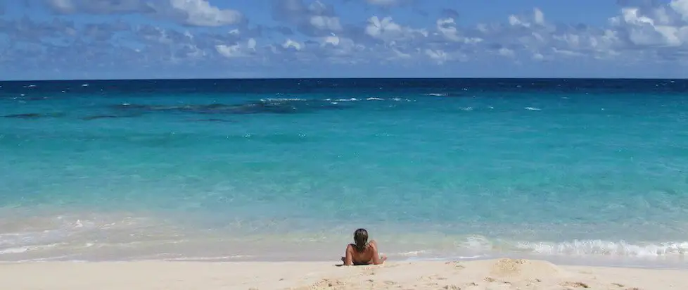 Een ongerept strand aan de prachtige kust van Bermuda met een persoon die uitrust in het ondiepe, heldere water