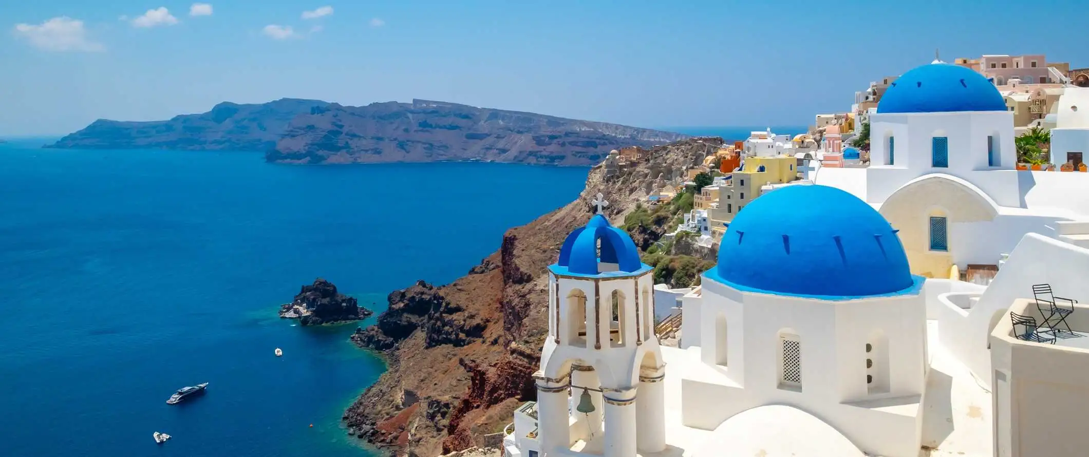 Edificios encalados con techos abovedados azules con vistas al Mediterráneo en Santorini, Grecia