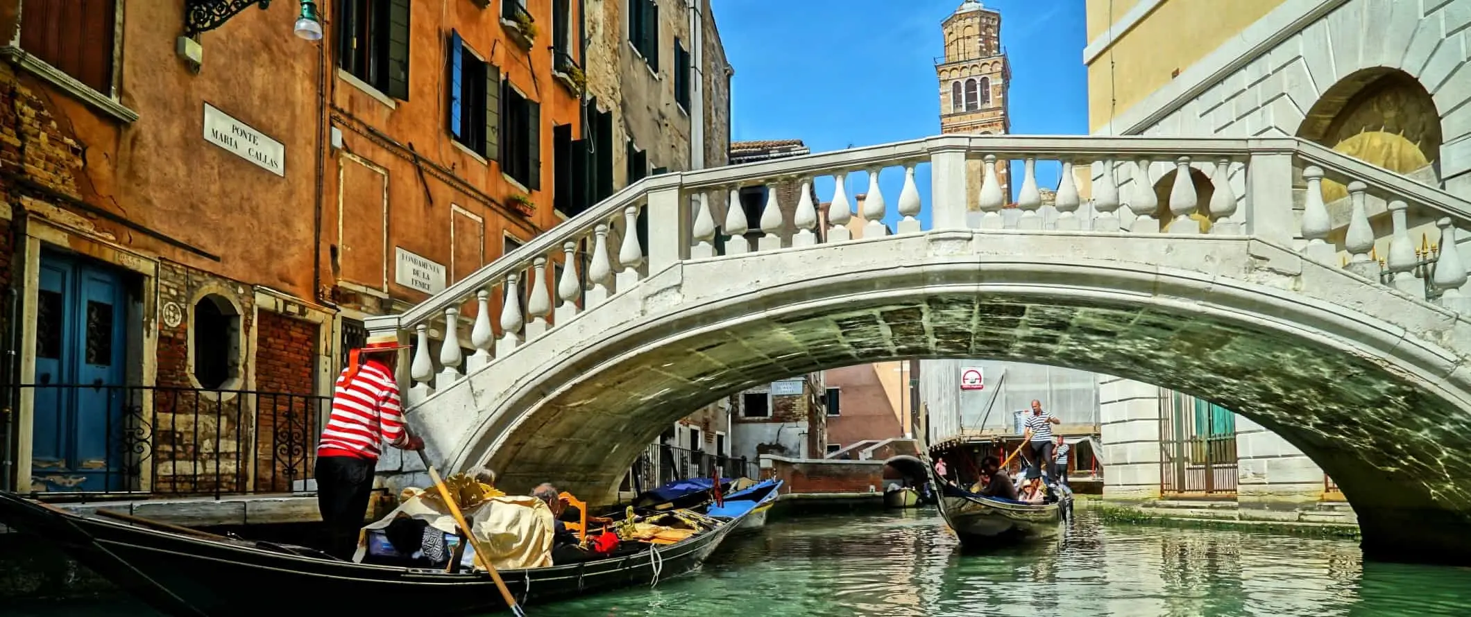 Uomo che guida una gondola attraverso un canale a Venezia, Italia