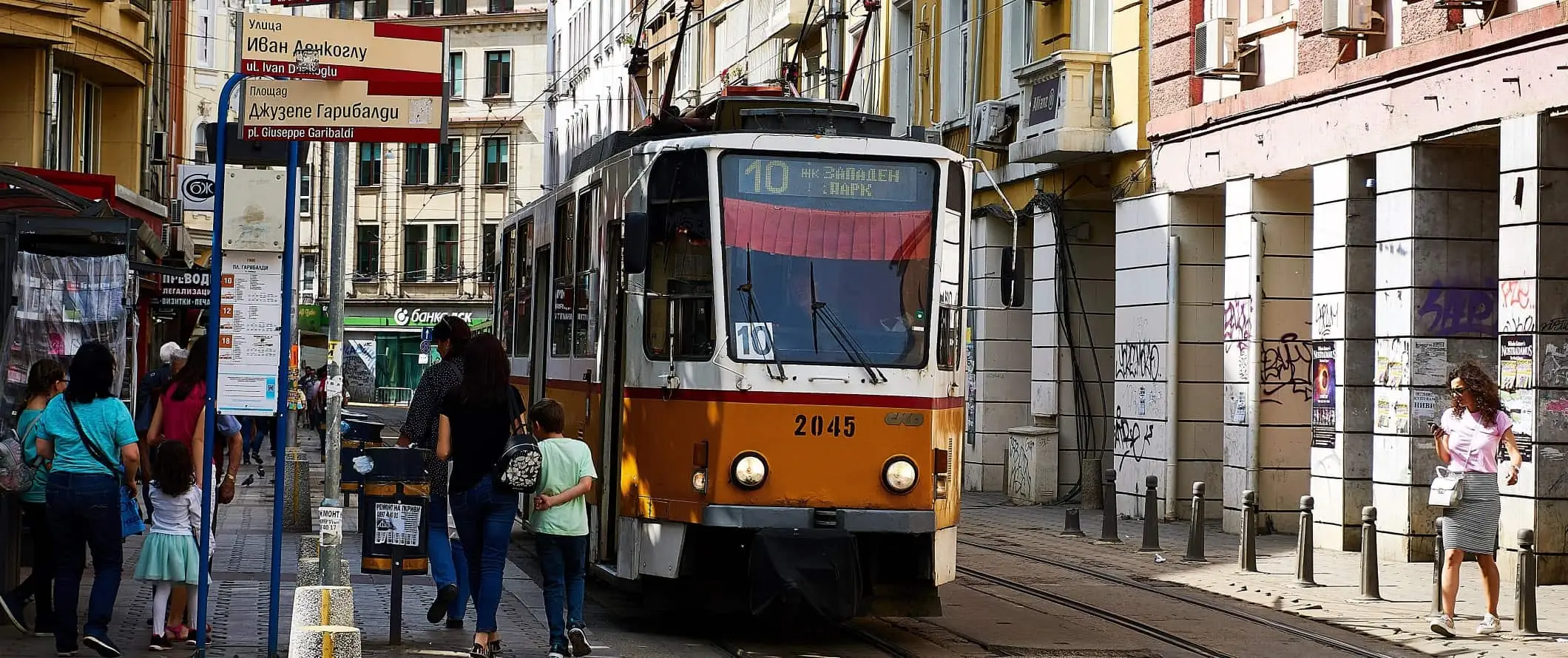 Žuti tramvaj koji se zaustavlja nasred ulice kako bi ljudi ušli u Sofiju, Bugarska