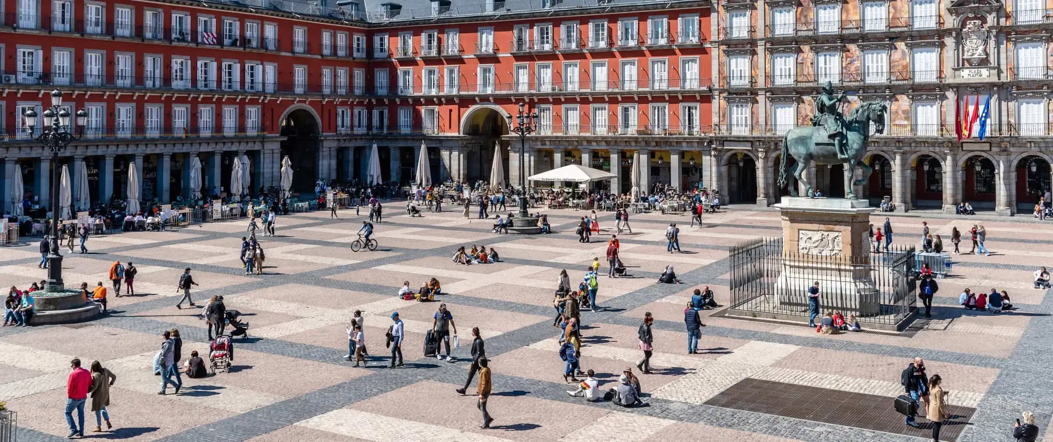 Pessoas relaxando e passeando por uma enorme praça em Madri, Espanha