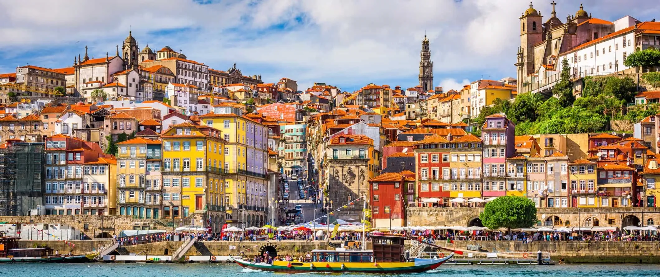 En båt som passerar den färgglada kusten i Porto, Portugal på en hektisk sommardag