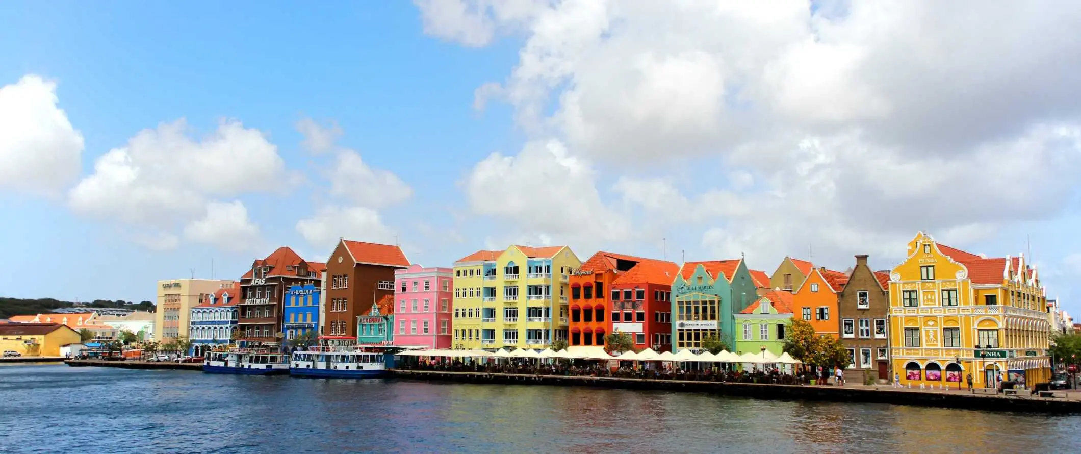 Fargerike hus og mennesker som spiser ute ved vannkanten på den tropiske øya Curaçao i Karibia