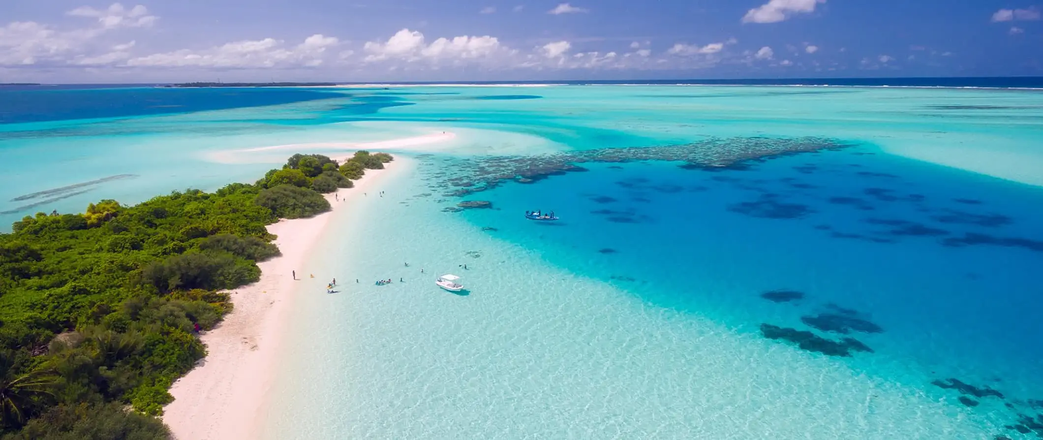 Det fantastiske, klare tropiske bluesvannet på Maldivene langs en smal, hvit sandstrand